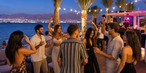 חופשה לרווקים ורווקות באילת – קבוצת חברים רוקדת במסיבת חוף מול הים והרי אדום