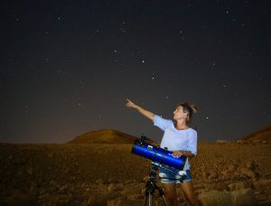 משתתפת ליד טלסקופ ומצביעה לשמי הכוכבים בתצפית באזור אילת