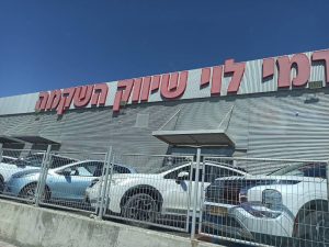 חזית סניף רמי לוי ברחוב הזגג באילת, עם שלט אדום וחניה